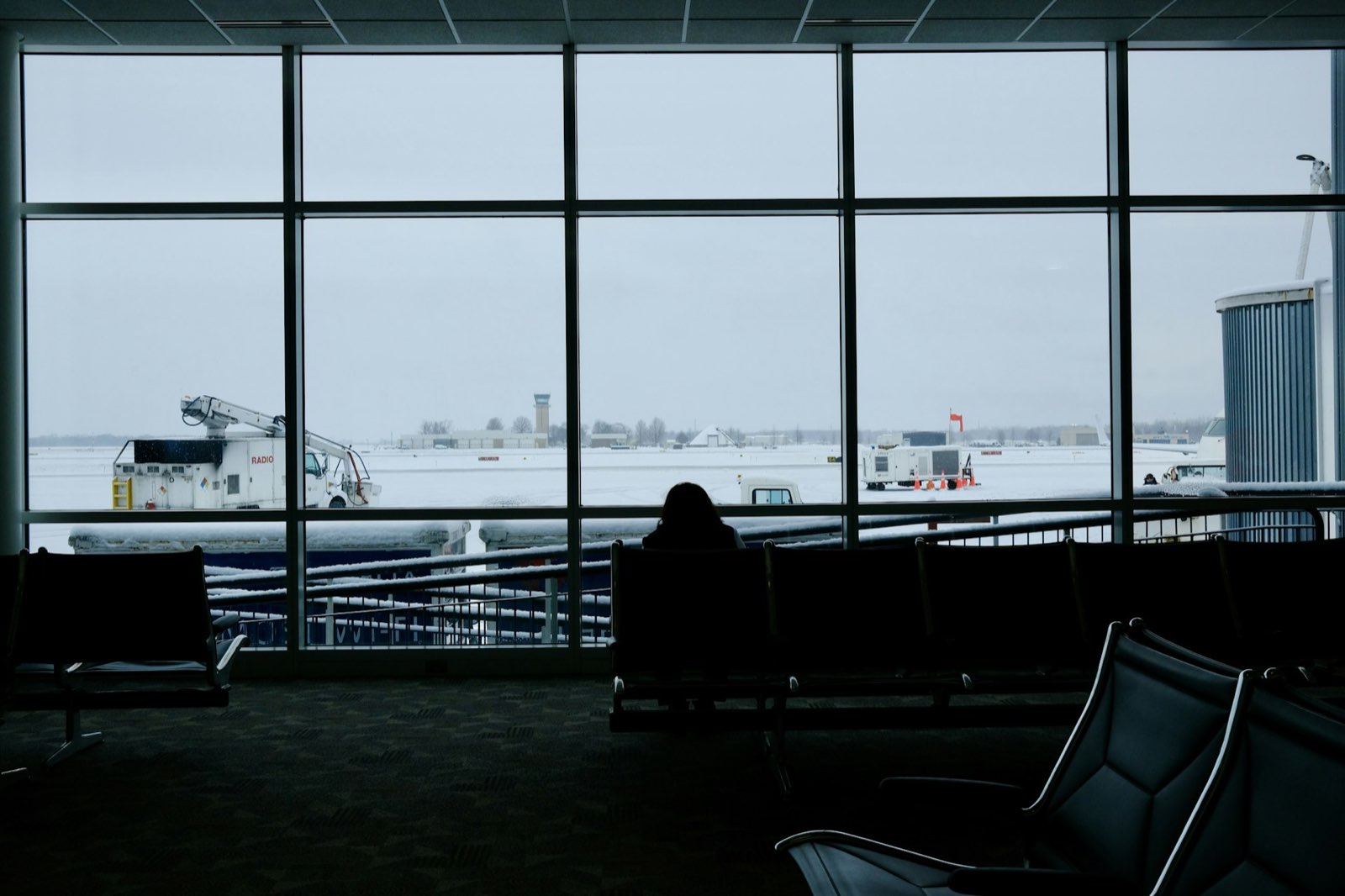 An airport gate lounge looking out on a snowy apron