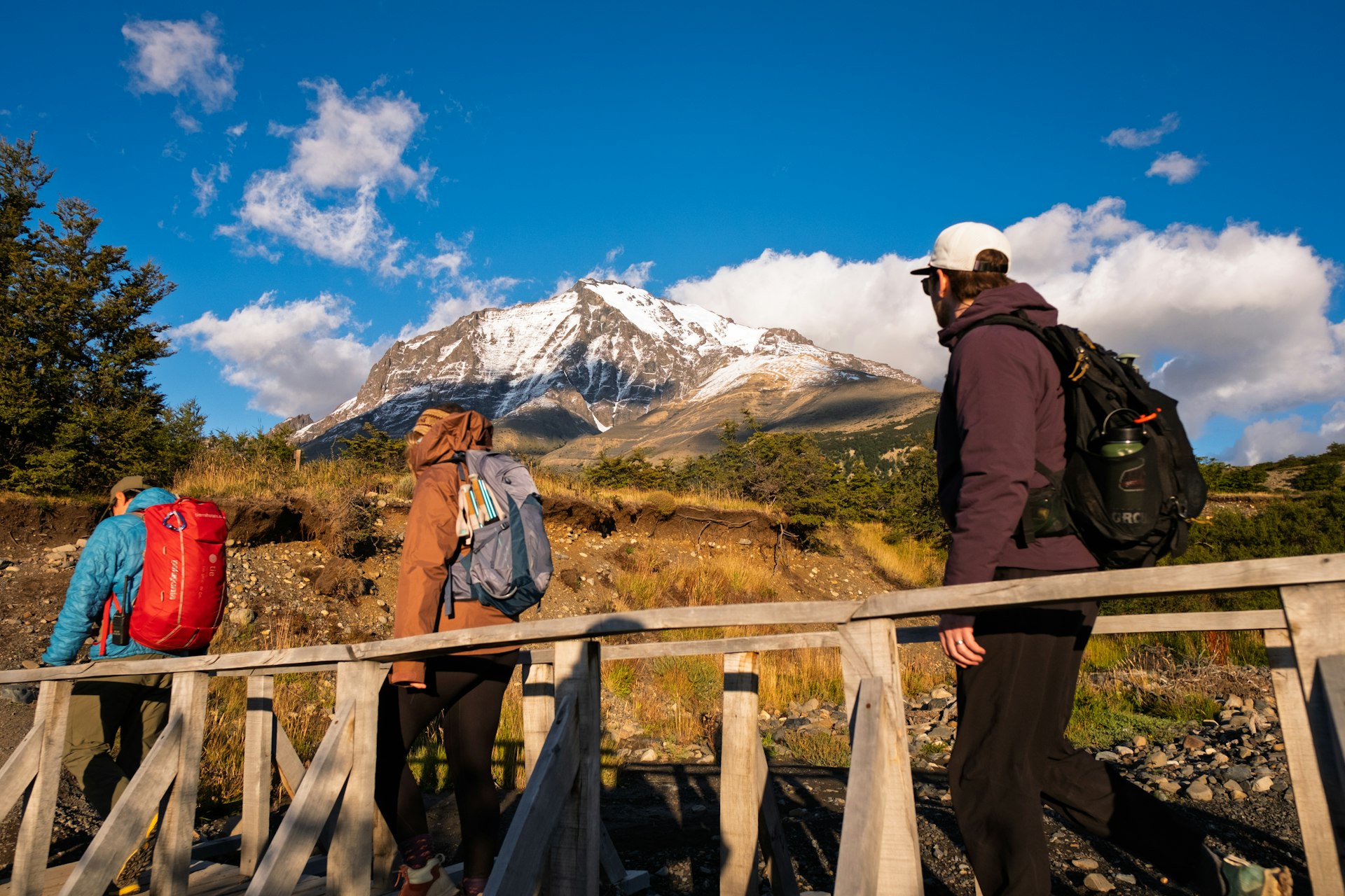 A family on a mountain trail with snow-capped peaks behind