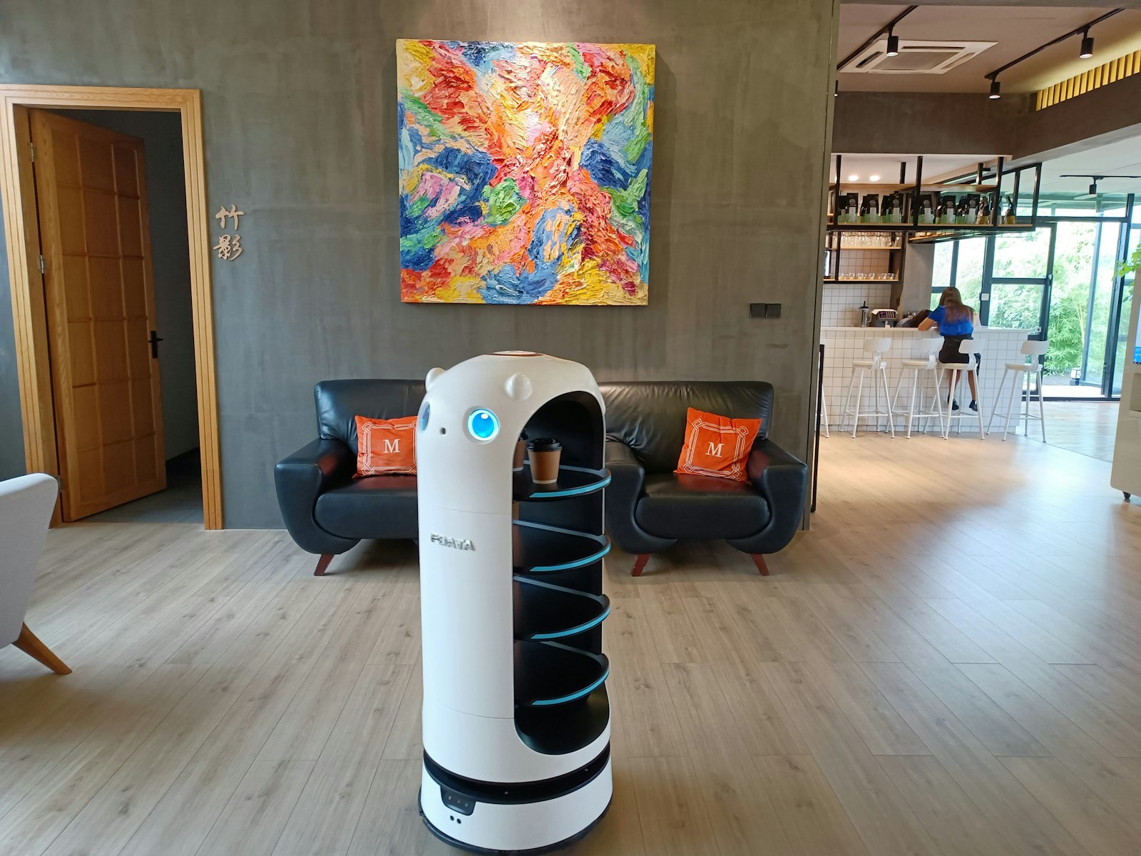 A service robot carrying a coffee through a hotel lounge