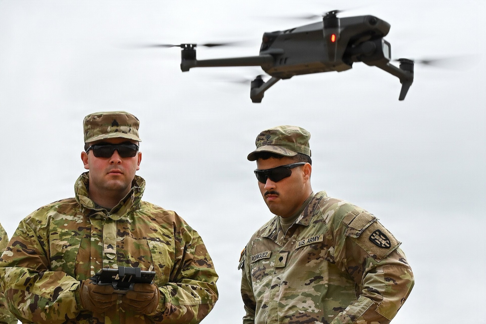 Two soldiers train with a small uncrewed aircraft hovering just above them